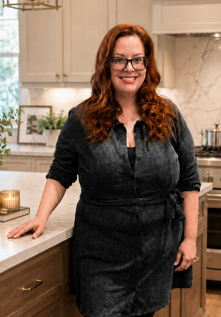 Candace, the kitchen and cabinetry designer behind Spaces by Candi, standing in a warm wood kitchen while holding a white cabinet door sample.